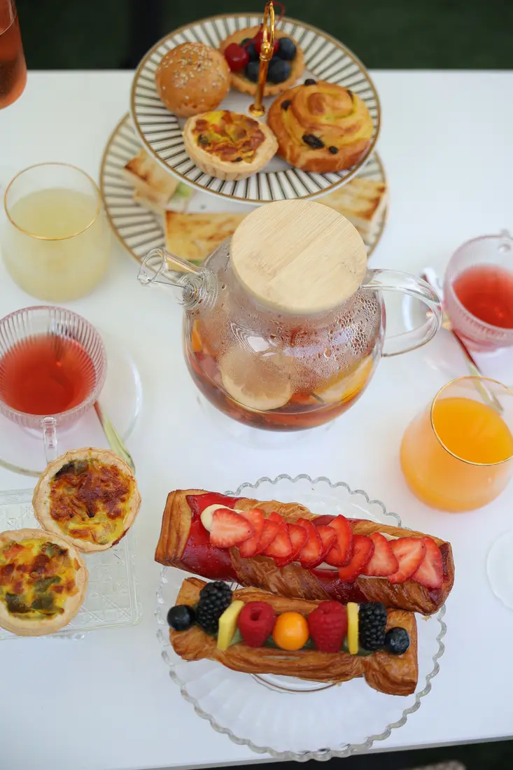 Afternoon tea at l'Accrasien: a tiered stand of pastries and quiches, a glass teapot and fresh juices
